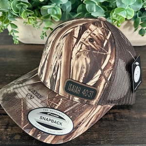 May include: Camouflage baseball cap with a brown mesh back and a curved brim. The cap features a patch with the text "ISAIAH 40:31" and a "Snapback" tag. The hat has a brown and tan pattern.