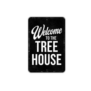 May include: A rectangular black metal sign with rounded corners featuring white text that reads Welcome TO THE TREE HOUSE. The sign has a distressed, weathered texture throughout the black background and includes small mounting holes at the top and bottom.
