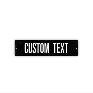 May include: A rectangular black metal sign with the words "CUSTOM TEXT" in white, centered on the sign. The sign has two small holes, one on each end. The background is white.