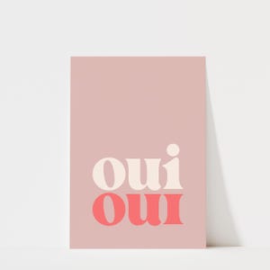May include: A rectangular wall art print featuring a dusty rose background. The word "oui" is printed twice in a stacked, bold, serif typeface. The top "oui" is in a creamy off-white color, while the bottom "oui" is in a vibrant coral pink.