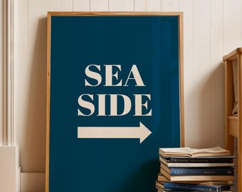 May include: A framed print with a dark blue background and white text that reads "SEA SIDE" with a white arrow pointing to the right.