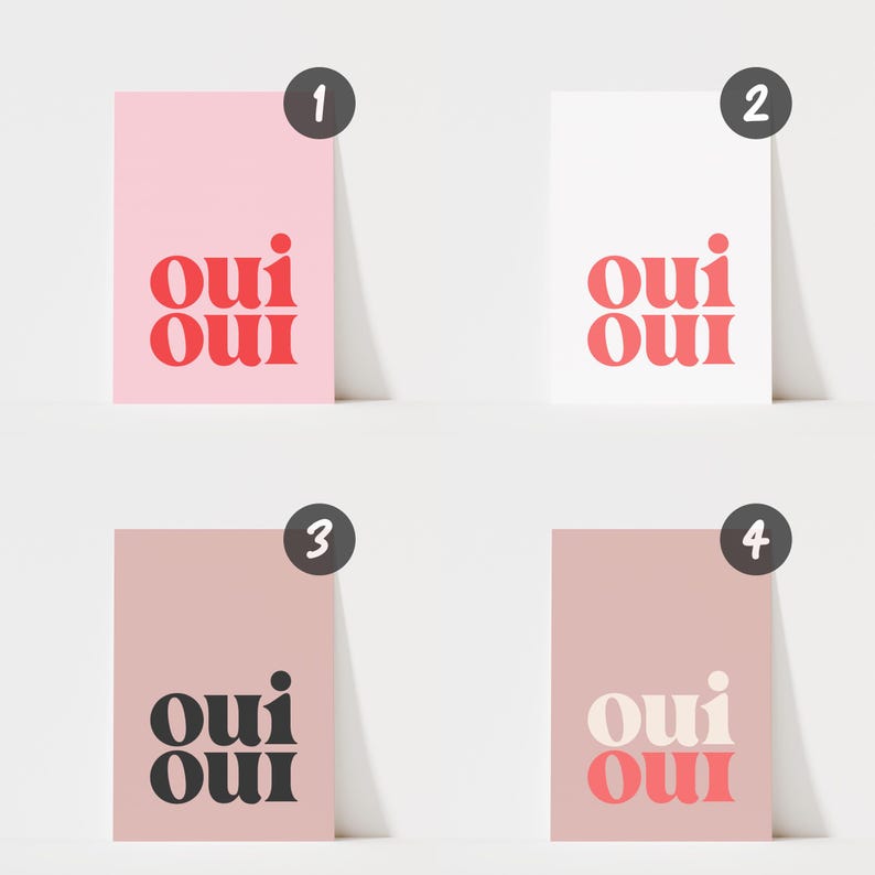 May include: Four rectangular art prints featuring the text "oui oui" in a bold, rounded font. Print one has a light pink background with red text. Print two has a white background with red text. Print three has a dusty rose background with black text. Print four has a dusty rose background with cream text.