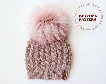 May include: A pink knitted beanie with a fluffy pom pom and a brown leather tag that says "Twisted".