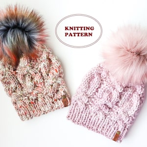 Op de afbeelding: Twee gebreide mutsen met nep bont pompoenen. Eén muts is roze en de andere is een mix van roze, wit, oranje en bruin. De mutsen hebben een kabelbreipatroon. De tekst "Knitting Pattern" staat in een rode ovaal.
