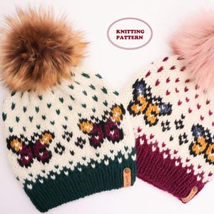 May include: Two knitted beanies with butterfly patterns. One beanie has a dark green brim and a brown faux fur pom-pom. The other has a burgundy brim and a pink faux fur pom-pom. The beanies have a cream-colored background with a repeating pattern of green and red hearts.