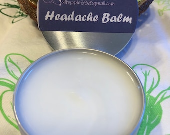 May include: A small, round, silver tin of Headache Balm with a white, creamy substance inside. The lid has a dark blue label with the words "Headache Balm" in white, and the email address oilhyppie88@gmail.com.