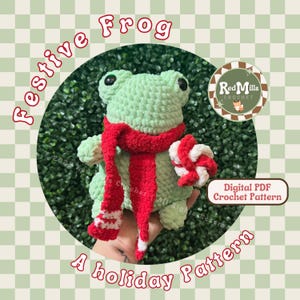 May include: A light green crocheted frog wearing a red scarf with white stripes and holding a red and white candy cane. The image includes the text "Festive Frog" and "A holiday Pattern".