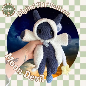 May include: A dark blue crocheted plush creature with large black eyes, wearing a white hooded cloak with a small light yellow star attached to the sleeve. The text Digital PDF Pattern and Moon Devil are visible in the image.