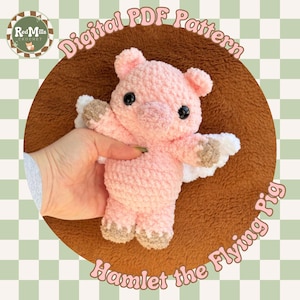 May include: A pink crocheted pig with small wings, black eyes, and brown hooves. The pig is labeled "Hamlet the Flying Pig" and is part of a "Digital PDF Pattern" from Red Mills Crochet.