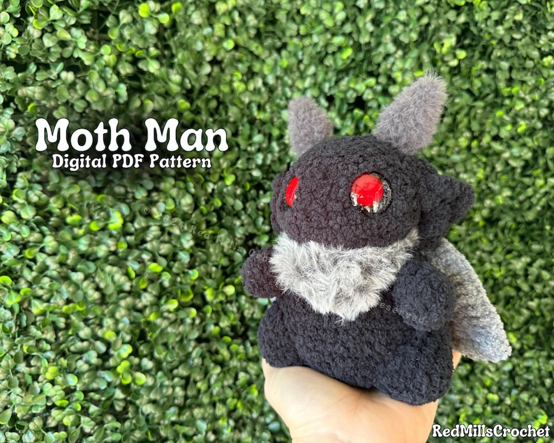 May include: A black and gray plush toy with red eyes, resembling a moth. The toy is being held in a hand. The text "Moth Man Digital PDF Pattern" is visible in the image.