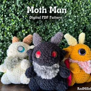 May include: Three crocheted plush toys in the shape of moths. The moths are in different colors: white, black, and orange. The white moth has a light blue eye, the black moth has a red eye, and the orange moth has an orange eye. The text "Moth Man Digital PDF Pattern" is at the top of the image.