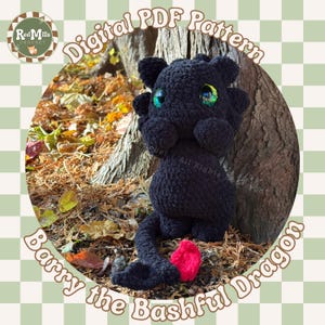 Könnte beinhalten: Ein schwarzes Häkeldrachen-Spielzeug mit großen, irisierenden grünen Augen und einem hellrosa herzförmigen Schwanz. Der Text "Digital PDF Pattern" und "Barry the Bashful Dragon" sind um das Bild herum angezeigt. Das Red Mills Crochet-Logo befindet sich in der oberen linken Ecke.