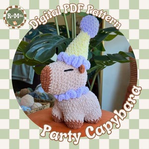 May include: A crochet capybara plush toy featuring a light brown body with a darker brown snout and feet. The capybara wears a party hat with a yellow cone, a purple pom-pom top, and a purple ruffled base. The text reads Digital PDF Pattern Party Capybara.