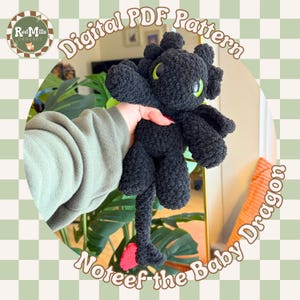 May include: A black crocheted dragon plushie with green eyes and a red heart-shaped detail on its tail. The dragon is held in a person's hand. The image includes text that says "Digital PDF Pattern" and "Noteef the Baby Dragon".