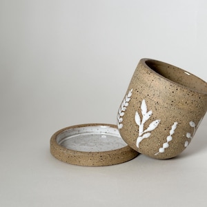 May include: A set of three ceramic vases in varying heights and shapes. The vases are glazed in a matte white finish, offering a minimalist aesthetic. The tallest vase is approximately 10 inches high.