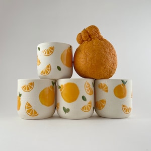 May include: A set of three ceramic mugs with a speckled, matte finish. Each mug features a different color: light blue, cream, and gray. The mugs have a simple, modern design and a comfortable handle.