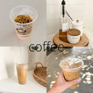 May include: Two iced coffees in clear plastic cups with lids. One cup has the text "Stay Grounded" on the side. The other cup is in a hand. The coffee is light brown and has ice cubes. The background is a white countertop with a wooden tray and a jar of honey.