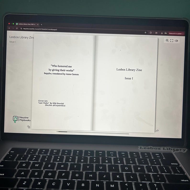 May include: A laptop displaying the open pages of a digital zine titled "Lesbos Library Zine, Issue 1." The left page features a quote by Sappho, translated by Anne Carson. The cover art is by Kiki Buccini. The laptop keyboard is visible.