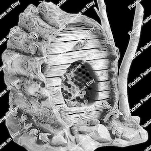 May include: A detailed, gray, sculpted beehive with a wooden door and honeycomb entrance. The beehive is surrounded by small, gray rocks and bees.