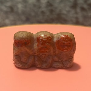 May include: Three small ceramic figurines of monkeys, each with a different expression. The monkeys are brown with red painted faces and are joined together.