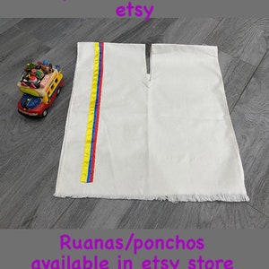 May include: White poncho with a yellow, blue, and red stripe down the side. The poncho has a fringe border. The text "Ruanas/Ponchos disponibles en tienda etsy" is at the top of the image. The text "Ruanas/ponchos available in etsy store" is at the bottom of the image.
