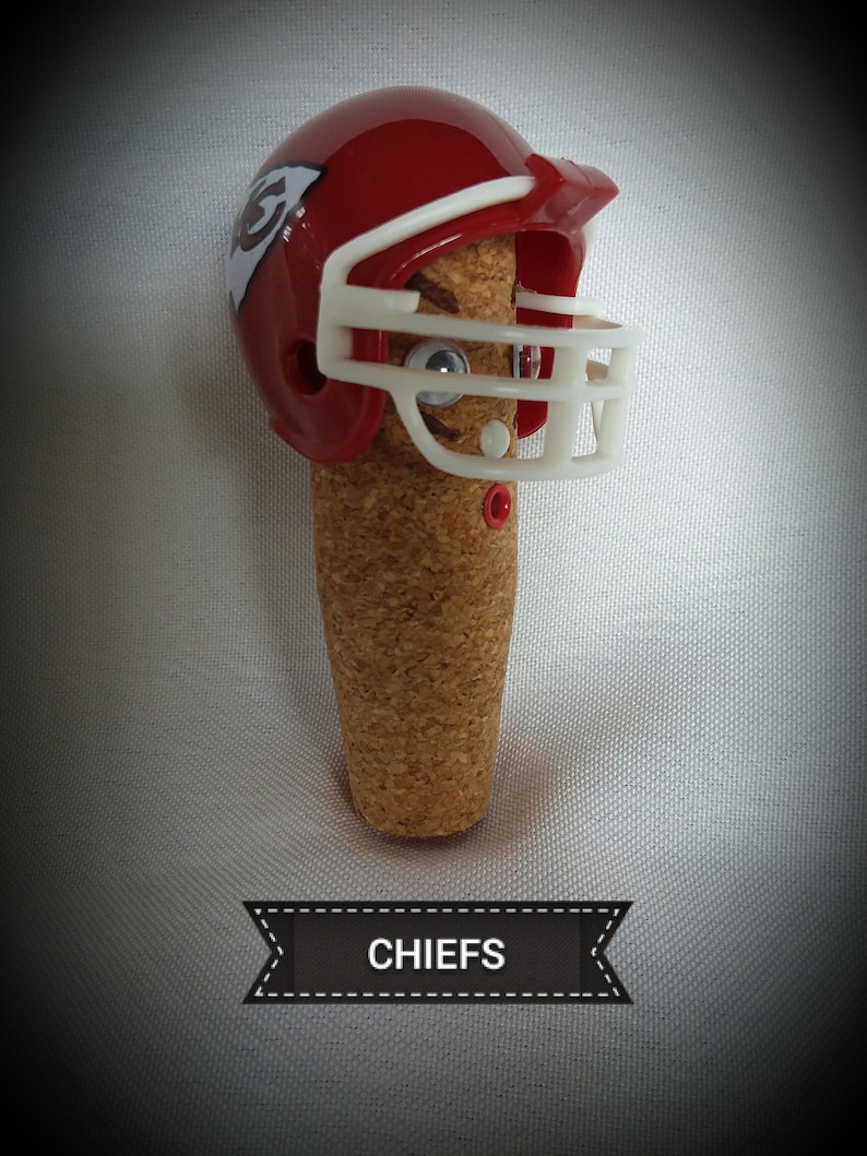 May include: A red and white football helmet with a cork body and the word "CHIEFS" on a black ribbon. The helmet has a white face mask and a red and white logo on the side.