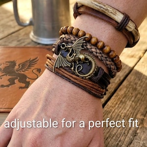 Puede incluir: Una colecci&oacute;n de pulseras de cuero marr&oacute;n con varios dise&ntilde;os, incluyendo un dije de drag&oacute;n y cuentas de madera. Las pulseras est&aacute;n apiladas en una mu&ntilde;eca, con el texto "adjustable for a perfect fit" en la parte inferior.
