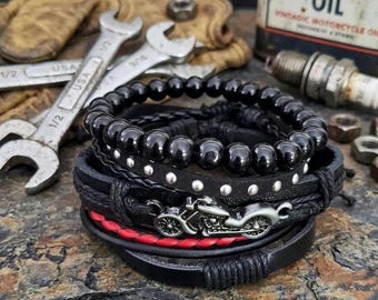 May include: A collection of black leather bracelets with silver studs and a motorcycle pendant. One bracelet has red detailing. The image also shows spanners, a vintage oil can, and a spark plug.