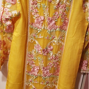 K&ouml;nnte beinhalten: Senfgelbe Tunika mit aufwendiger rosa Blumenstickerei. Die Tunika hat einen transparenten &Uuml;berzug auf den &Auml;rmeln und dem R&uuml;cken, mit zarten Spitzenbesatz. Ein sch&ouml;nes Kleidungsst&uuml;ck.