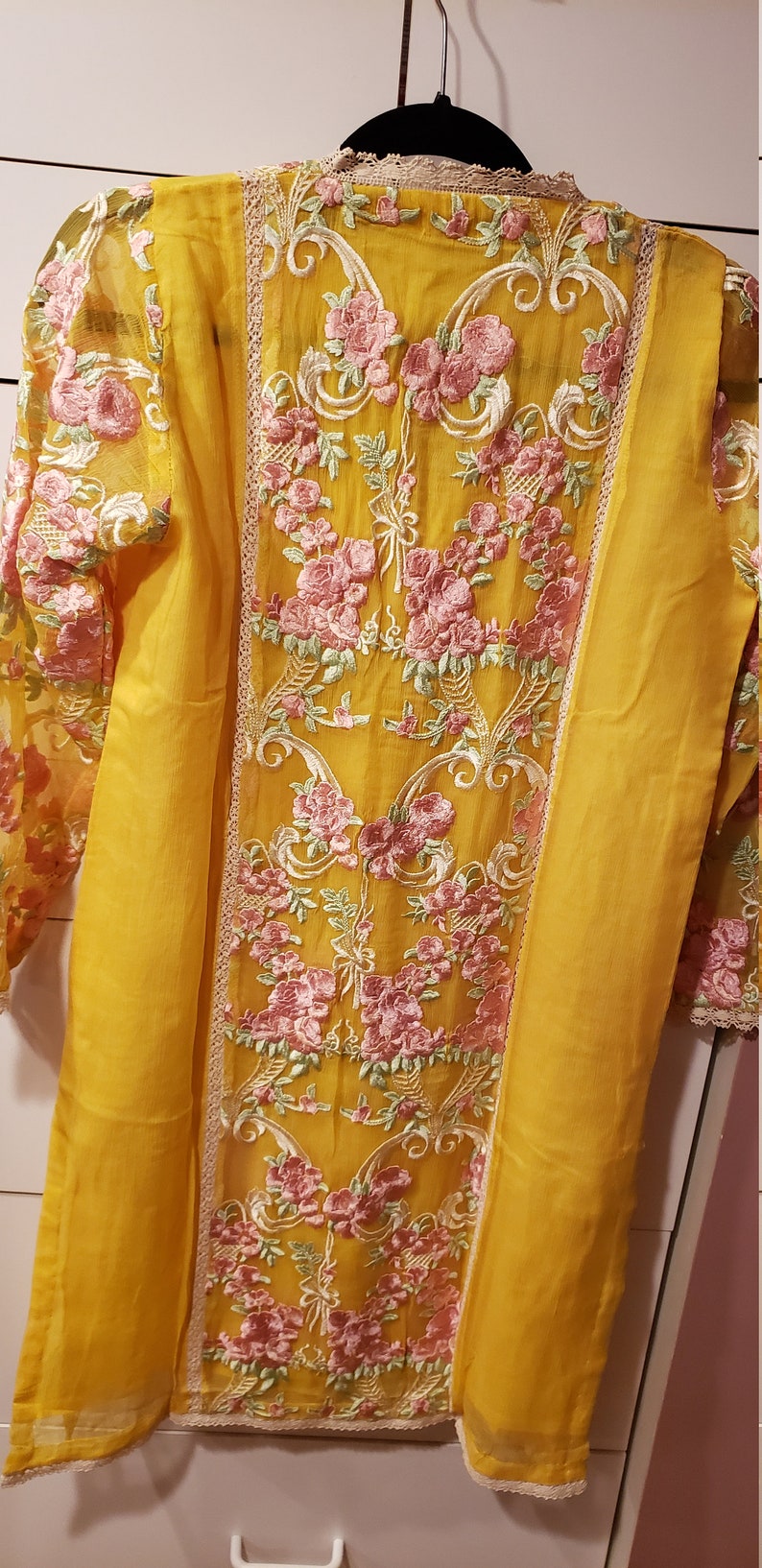 K&ouml;nnte beinhalten: Senfgelbe Tunika mit aufwendiger rosa Blumenstickerei. Die Tunika hat einen transparenten &Uuml;berzug auf den &Auml;rmeln und dem R&uuml;cken, mit zarten Spitzenbesatz. Ein sch&ouml;nes Kleidungsst&uuml;ck.