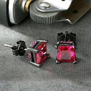 May include: A pair of black stud earrings featuring square-shaped red gemstones. The earrings have a black metal setting and are designed for pierced ears.