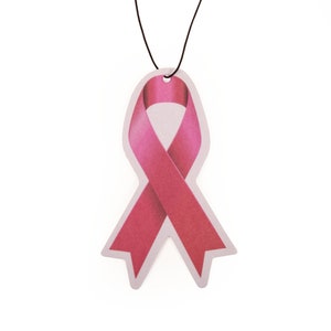 May include: Pink ribbon car air freshener hanging from a black string. The ribbon is a symbol of breast cancer awareness.