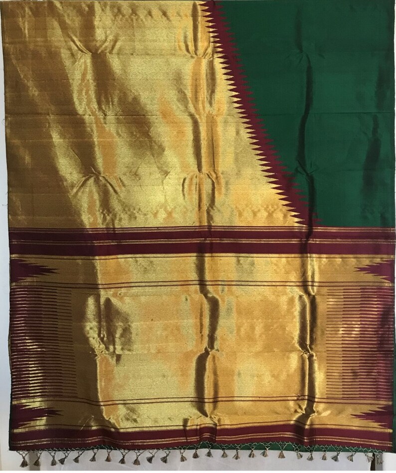 May include: A traditional Indian saree with a gold and green color scheme. The saree has a maroon border with a geometric pattern. The fabric is a silk blend.