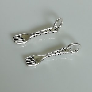 Op de afbeelding: Twee zilveren vorkcharms met een gedraaid ontwerp. De charms hebben een lus aan de bovenkant om aan een armband of ketting te bevestigen.