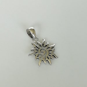May include: Silver pendant charm in the shape of a sun with a spiral design in the centre.