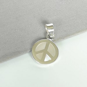 May include: A silver peace sign pendant with a white mother of pearl inlay.