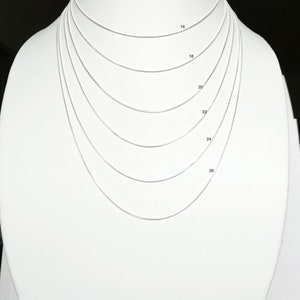 Może przedstawiać: Srebrny naszyjnik w postaci łańcuszka prezentowany na białym manekinie. Naszyjnik jest pokazany w różnych długościach, od 40,6 cm do 66 cm.