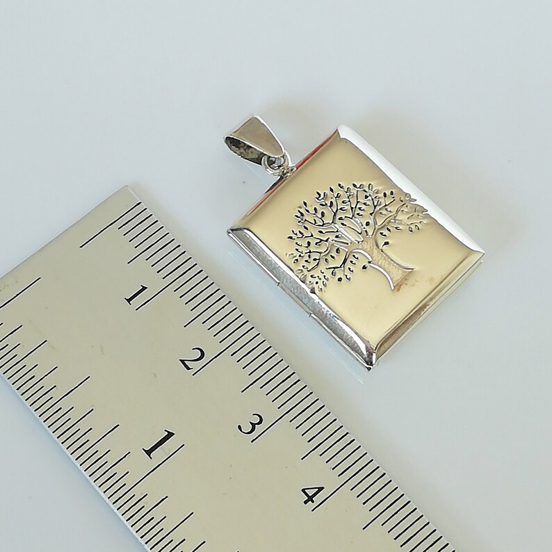 May include: Silver locket pendant with a tree of life design. The locket is approximately 1 1/2 inches in length.