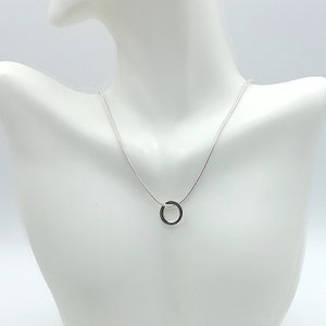 Puede incluir: Un collar de cadena de plata con un simple colgante circular.