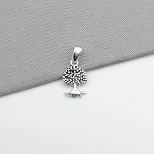Op de afbeelding: Een zilveren boom des levens hanger. De hanger is gedetailleerd met een textuurontwerp en heeft een kleine lus aan de bovenkant om aan een ketting te bevestigen.