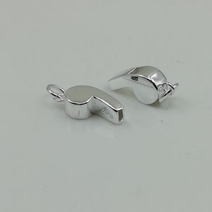 Puede incluir: Dos abalorios de plata en forma de silbato, uno con un bucle para sujetarlo a un collar o una pulsera. Los abalorios son detallados y realistas.