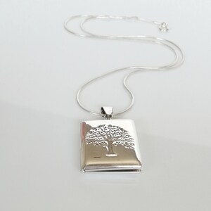 May include: A silver necklace with a square pendant featuring an etched tree of life design.