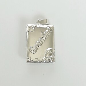 May include: Silver locket pendant with the word "Grandma" engraved on the front. The locket has a small design of a child on the bottom.