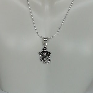 May include: A silver chain necklace with a silver pendant featuring a detailed depiction of the Hindu deity Ganesha.