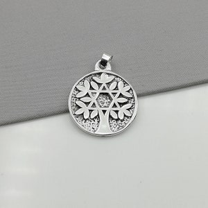 May include: Silver pendant featuring a tree of life design with a Star of David in the center. The pendant is round and has a textured surface.