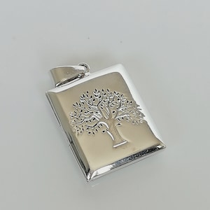 Può includere: Ciondolo a forma di medaglione in argento con un design ad albero della vita. Il medaglione è rettangolare e ha una finitura liscia e lucida.