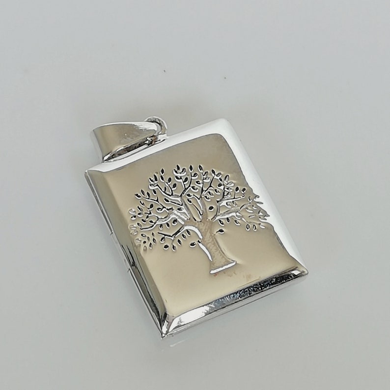 May include: Silver locket pendant with a tree of life design. The locket is rectangular and has a smooth, polished finish.