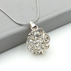 May include: A silver chain necklace with a silver pendant that is a sphere of interwoven silver strands.
