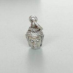 Puede incluir: Encanto de plata con una representación detallada de la cabeza de Buda. El encanto tiene un bucle para sujetarlo a una pulsera o collar.