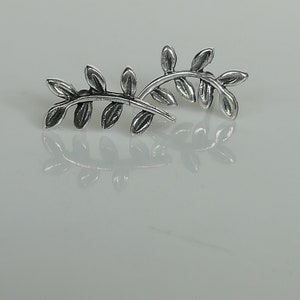May include: A pair of silver earrings shaped like a branch with leaves.